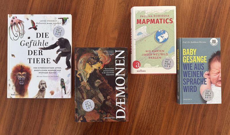 Vier Bücher auf einem Holzboden.